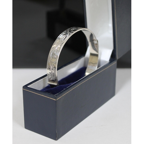 146 - A hallmarked silver hinge bangle with engraved decoration to outer edge, diameter 6.5cm, gross weigh... 