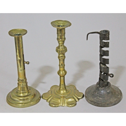 296 - A group of three antique candlesticks comprising an 18th Century hog scraper, a petal based brass ca... 