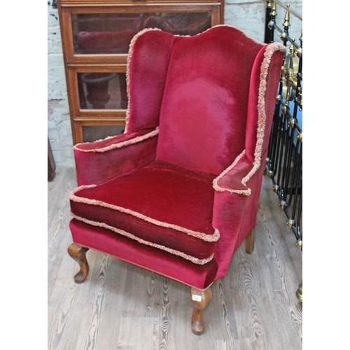 76 - A red velvet wing back chair.