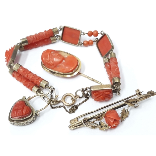 100G - A suite of yellow metal and carved coral jewellery comprising a bracelet, a brooch and stick pin, un... 