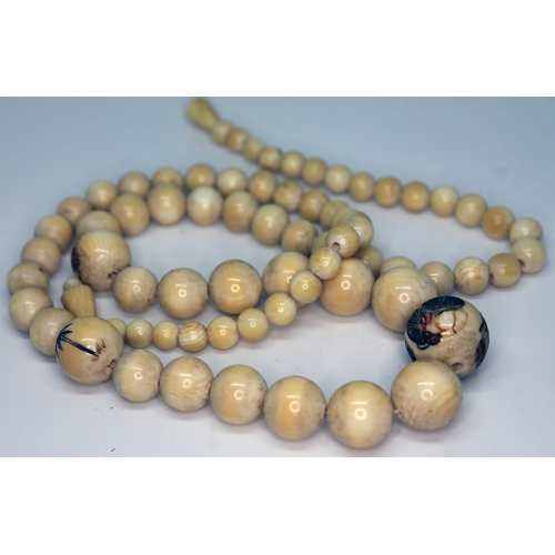 94 - A Japanese Meiji period ivory bead necklace, three beads carved with animals, length 56cm, wt. 37g.