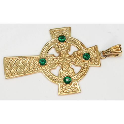 141 - A 9ct gold Celtic style cross set with green stones, marked '9K' and also with 9ct gold import marks... 