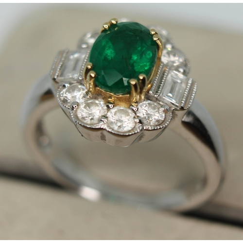 171 - A contemporary Art Deco style emerald and diamond cluster ring, the oval cut emerald set within a su... 