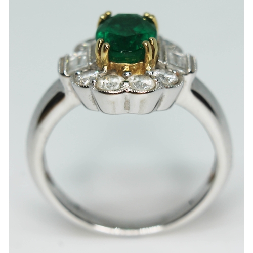 171 - A contemporary Art Deco style emerald and diamond cluster ring, the oval cut emerald set within a su... 