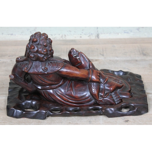 47 - A Chinese carved hardwood figure depicting a seated man with fish on base, length 40cm.