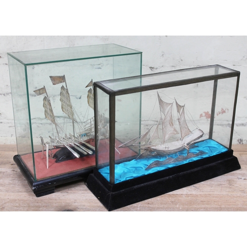 228 - Two eastern white metal model boats within glass display cases.