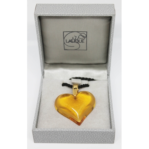 231 - A Lalique amber glass heart shaped pendant with yellow metal loop and black cord necklace, with orig... 