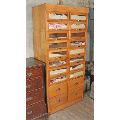 66 - A light wood haberdashery cabinet comprising 16 glazed drawers with chrome handles over four lower d... 