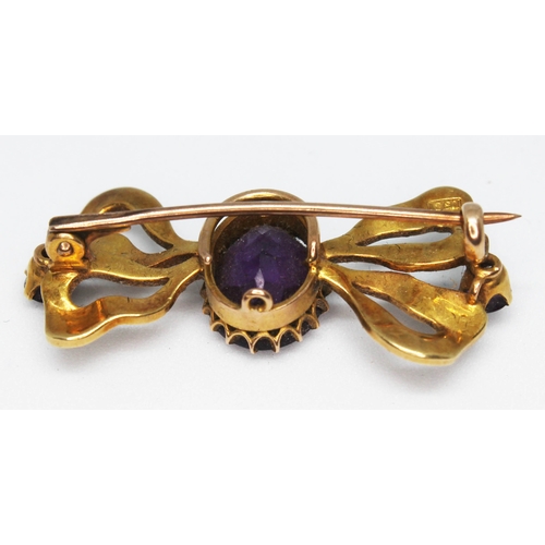 108 - A 15ct gold brooch of bow form and set with amethyst coloured stones and split pearls, marked '15ct'... 