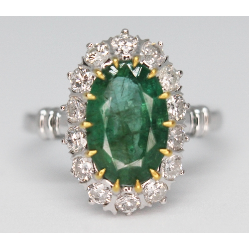 174 - An emerald and diamond ring, the central oval cut and claw emerald approx. 2.40ct, surrounded by fou... 