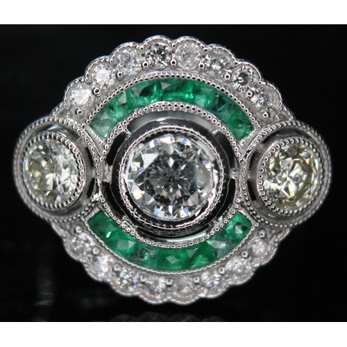 177 - An Art Deco style diamond and emerald ring, featuring three round brilliant cut diamonds surrounded ... 