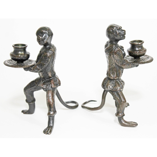 426 - A pair of bronze candlesticks each formed as a fully clothed monkey and holding a platter, height 16... 