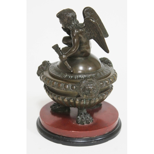 427 - A bronze inkwell formed as a cherub sat on a domed lid above the gadrooned base with lion masks and ... 