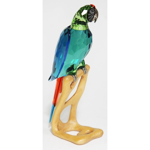 439 - A Swarovski Paradise Birds parrot on naturalistically formed wooden stand, height 23cm.