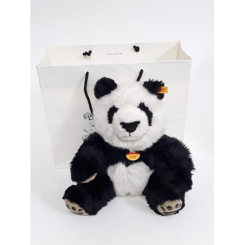 516 - A Steiff Manschli Panda Bear 25cm no. 064258, with button to ear, tags, Steiff box and paper bag.