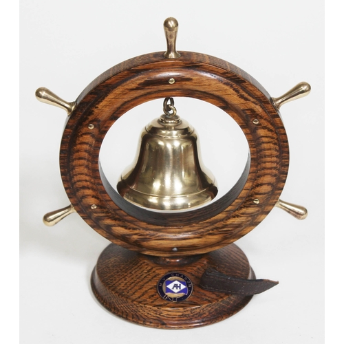 263 - A ship souvenir brass bell and striker within oak wheel frame and oak base labelled 'M.V. Charon' (A... 