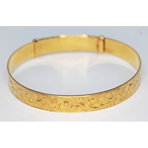 102 - A hallmarked 18ct gold bright cut engraved and adjustable bangle, wt. 30.93g.