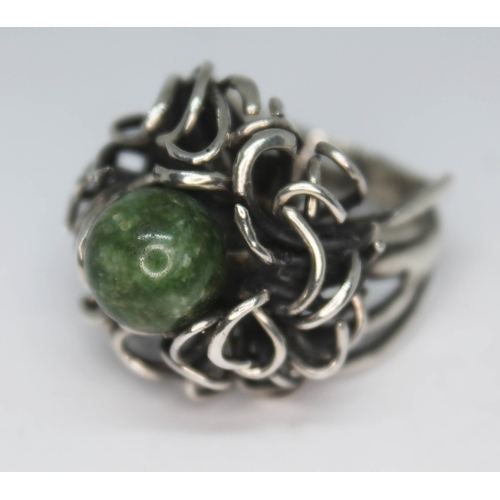 293 - A contemporary white metal ring with random wire setting supporting a jadeite bead, band unmarked, g... 