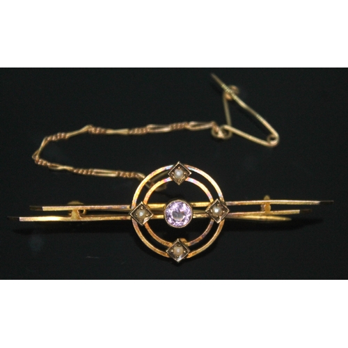 294 - An Edwardian bar brooch set with a central facetted amethyst within two concentric circles set with ... 