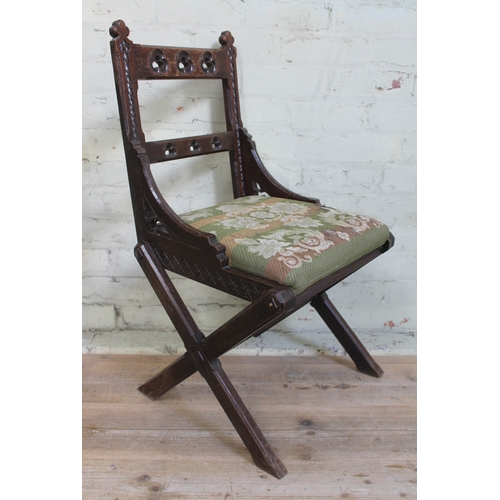 56 - An ecclesiastical oak chair with X frame and pierced back.