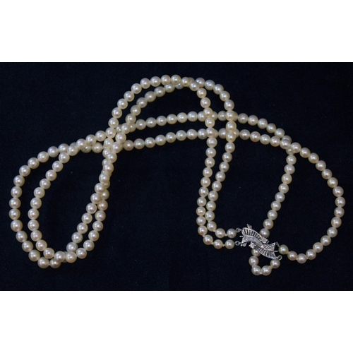 105 - A two strand cultured pearl necklace with white metal diamond set clasp marked '9c', pearls ranging ... 