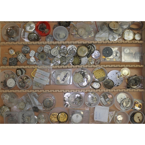 114 - A wooden tray containing mainly wristwatch parts including dials, movements, etc.