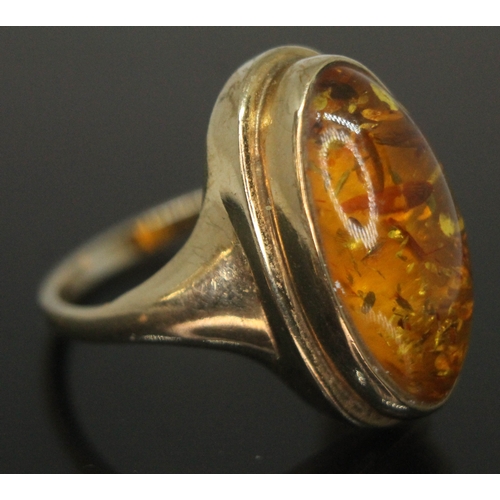 201 - A hallmarked 9ct gold ring set with an oval amber cabochon, measuring approx. 19mm x 9mm x 5mm.