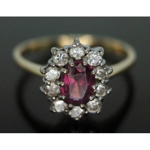 378 - A cluster ring set with a central oval cut pinkish purple almandine garnet and surrounded by ten rou... 