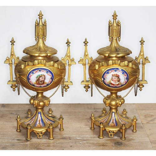 320 - A pair of ormolu and porcelain urns, architectural style with finials, handles and bows, each with a... 