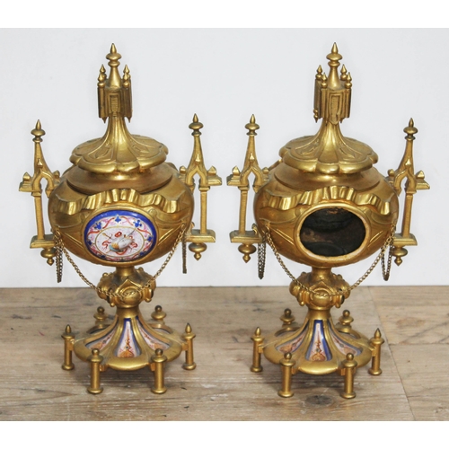 320 - A pair of ormolu and porcelain urns, architectural style with finials, handles and bows, each with a... 