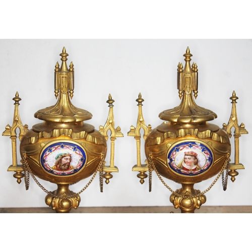 320 - A pair of ormolu and porcelain urns, architectural style with finials, handles and bows, each with a... 