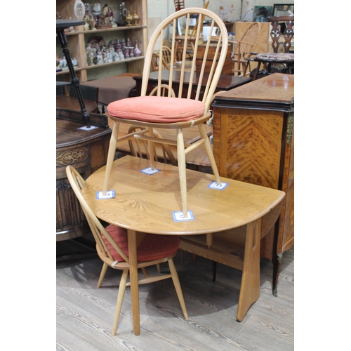 64 - An Ercol blonde drop leaf table and two chairs.