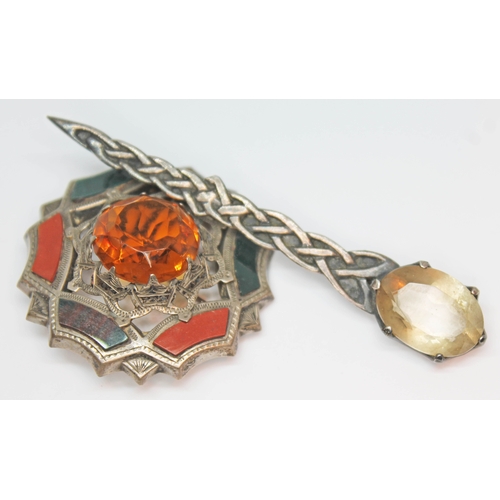 143 - A vintage Scottish silver brooch formed as a Celtic braid and set with an oval mixed cut smokey quar... 