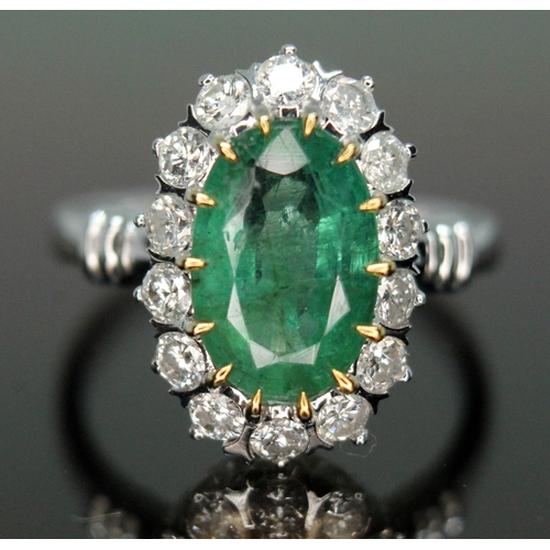 195 - An emerald and diamond ring, the central oval cut and claw emerald approx. 2.40ct, surrounded by fou... 