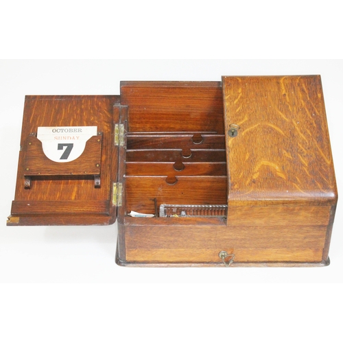 58 - An oak fold out stationary box with calendar, length 39cm.
