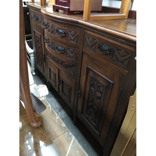 954 - An antique mahogany sideboard with carved door panels and drawer fronts and aesthetic handles.