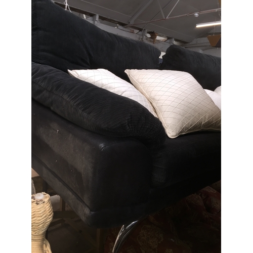 1009 - A black upholstered three seater sofa with additional white/cream cushions