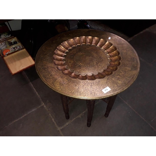 879 - An eastern brass top carved base folding table, diam. 61cm, height 53cm.