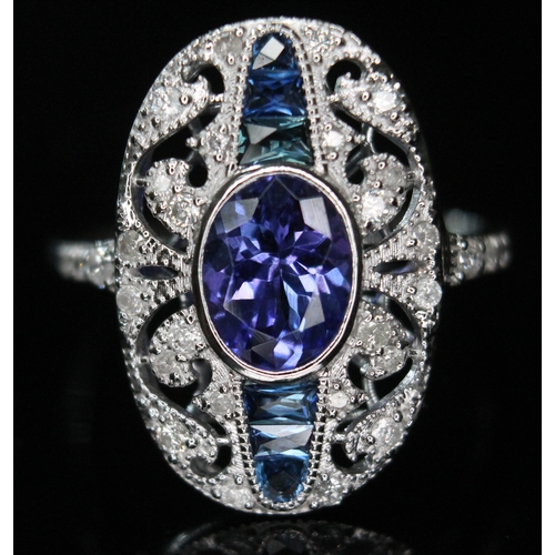 141 - A tanzanite, sapphire and diamond cluster ring, the central oval cut and bezel set tanzanite approx.... 