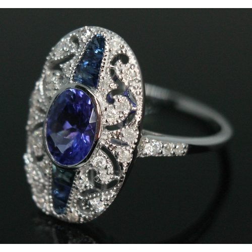 141 - A tanzanite, sapphire and diamond cluster ring, the central oval cut and bezel set tanzanite approx.... 