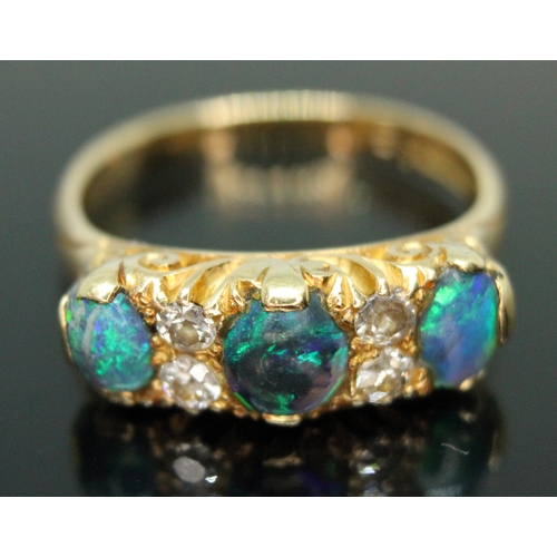 133 - An early 20th century black opal and diamond ring, scroll setting set with three precious black opal... 