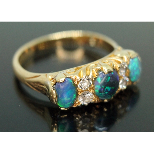 133 - An early 20th century black opal and diamond ring, scroll setting set with three precious black opal... 