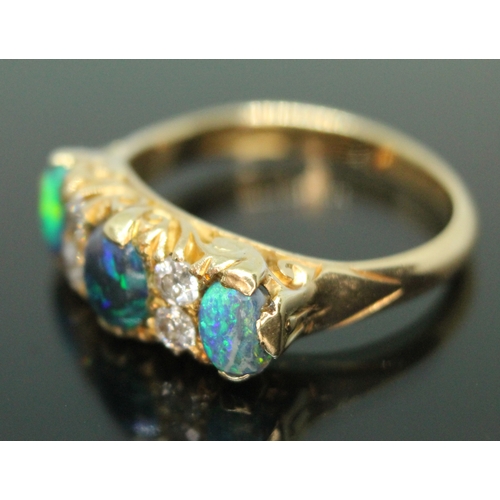 133 - An early 20th century black opal and diamond ring, scroll setting set with three precious black opal... 