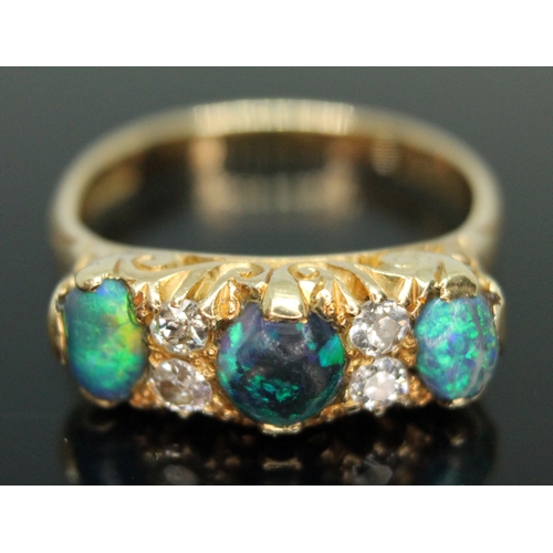 133 - An early 20th century black opal and diamond ring, scroll setting set with three precious black opal... 