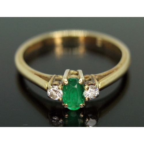 138 - An emerald and diamond ring, the central oval cut emerald measuring approx. 5mm x 3mm, the two moder... 