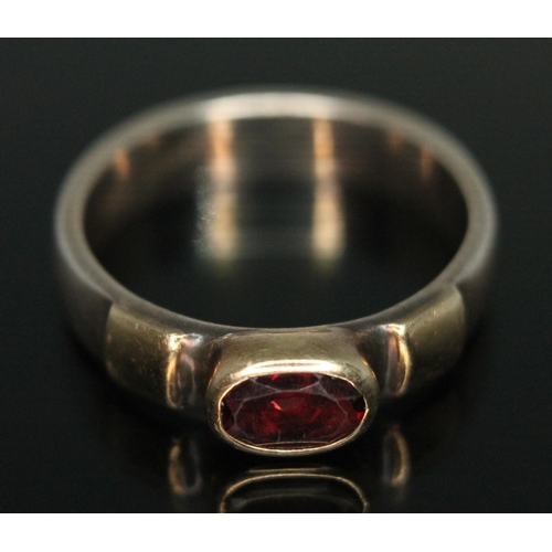 191 - A two colour ring set with an oval cut garnet, marked '375', gross weight 4.85g, size Q/R.