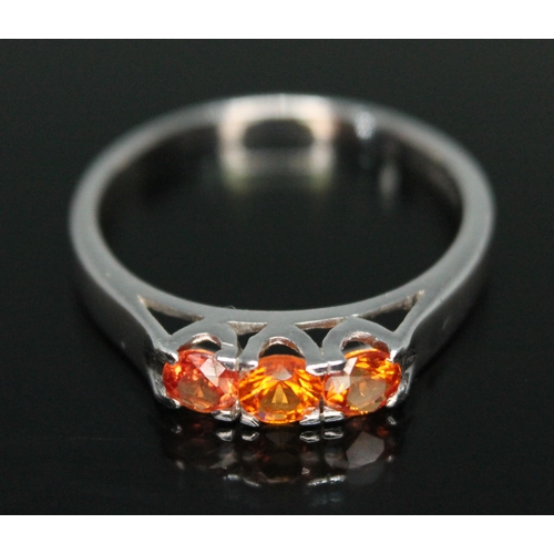 205 - A three stone fancy orange sapphire ring, hallmarked 9ct white gold band, sponsor's initials 'DK', B... 