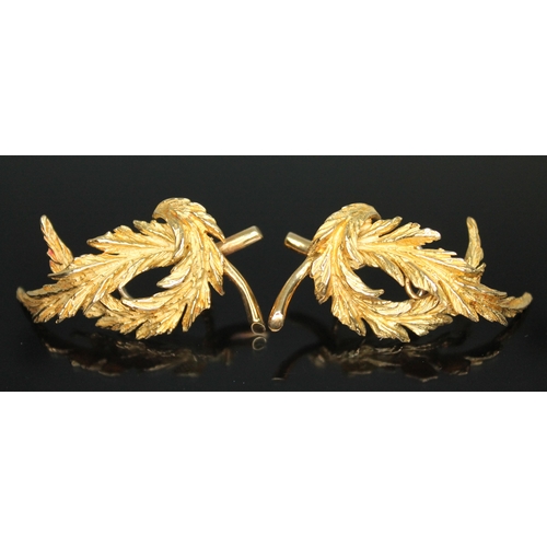 173 - A pair of 18ct gold clip on earrings, each naturalistically modelled as a pair of curved laurel wrea... 