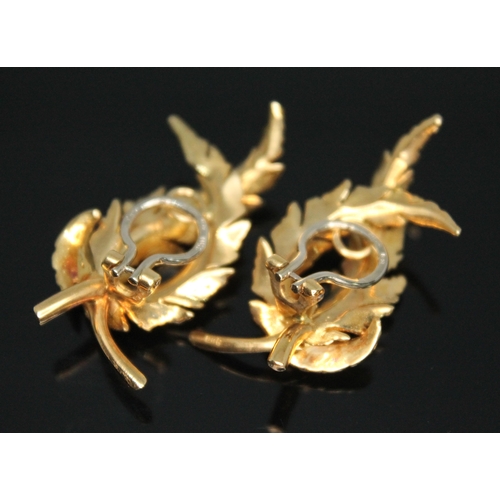 173 - A pair of 18ct gold clip on earrings, each naturalistically modelled as a pair of curved laurel wrea... 