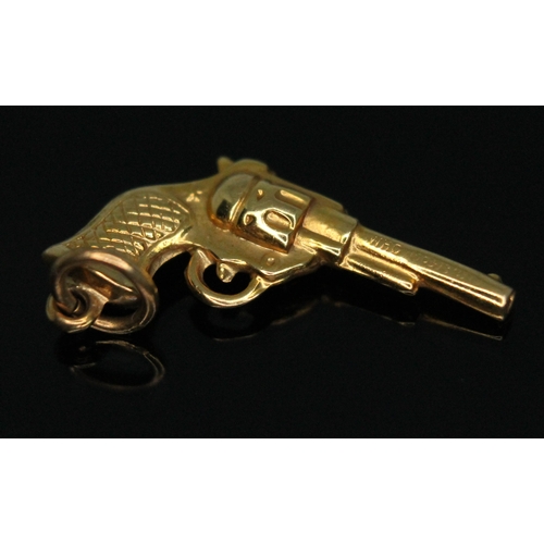 141 - A hallmarked 9ct gold novelty charm modelled as a revolver, wt. .067g, length 22mm.